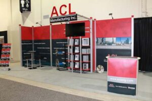 10x20 trade show booth at the Global Energy Show in Calgary, Alberta. This Octanorm booth holds a monitor and shelving, along with a branded podium, seating area, and custom dimensional signage.