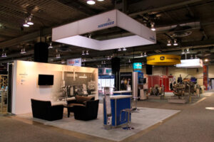 20x20 trade show booth with a beMatrix graphic wall, hanging fabric signage, meeting area, and portable podiums.