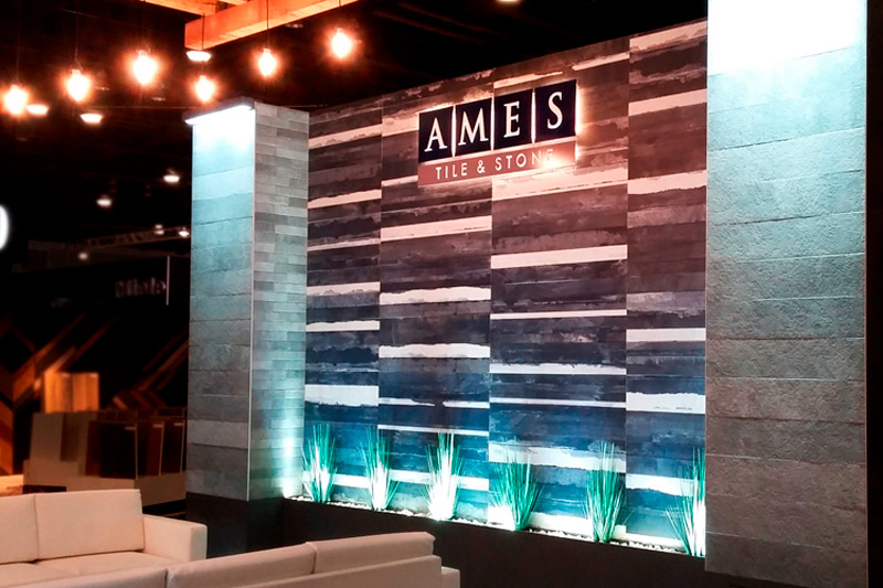 featured bal wall of a 20x20 trade show booth in Vancouver. The back wall is mde of custom tiles and stone pillars, with plant boxes that are backlit. A dimensional logo sign and custom lighting sits at the top of the display overhead. 