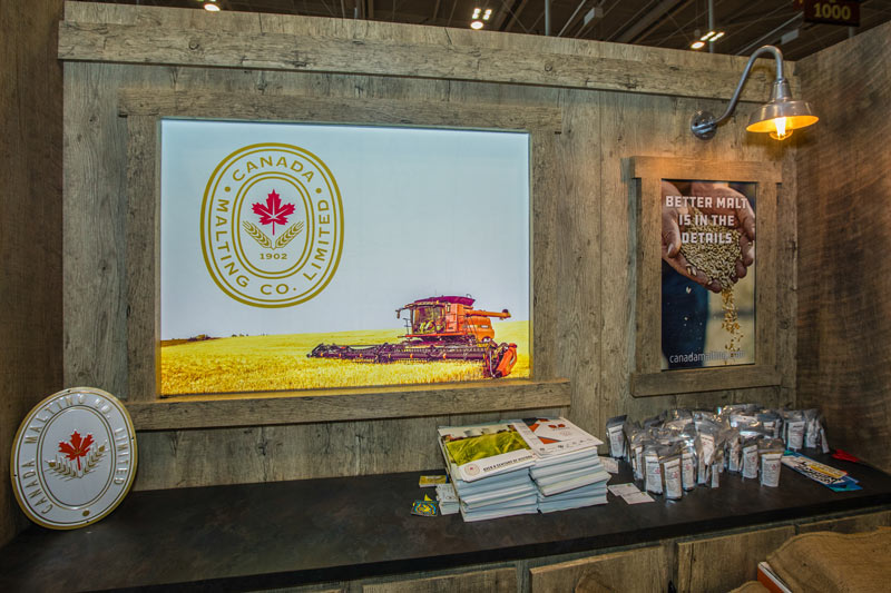 close up of a fabric backlit panel showing a combine in a Canadian field. There are also custom poster frames, lighting, and dark countertops. 