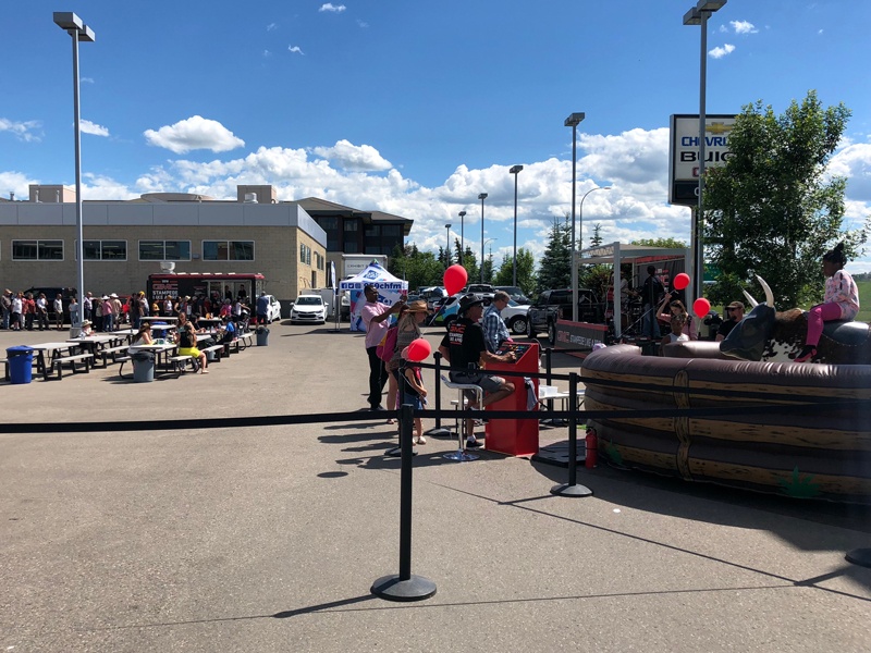 Calgary GMC dealership stampede event with a mechanical bull, food truck, and outdoor seating area