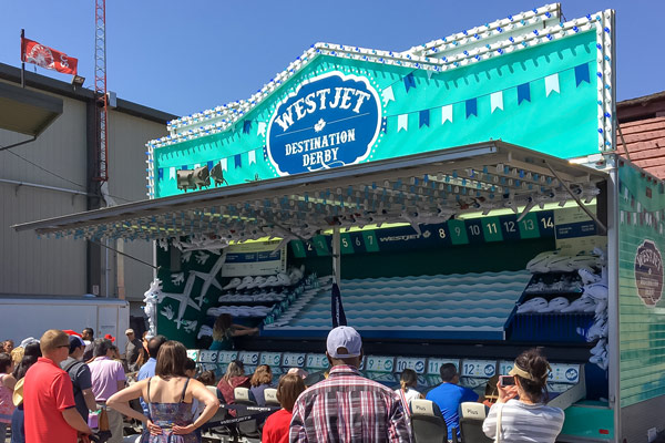 a mobile midway game trailer for the Calgary Stampede. Custom fabricated and branded in Westjet's colours so that multiple players can try and race airplanes cutouts down the length of the trailer to try and win prizes. A row of custom airplane seats and individual control stations are placed in front of the game for users to sit at and compete.