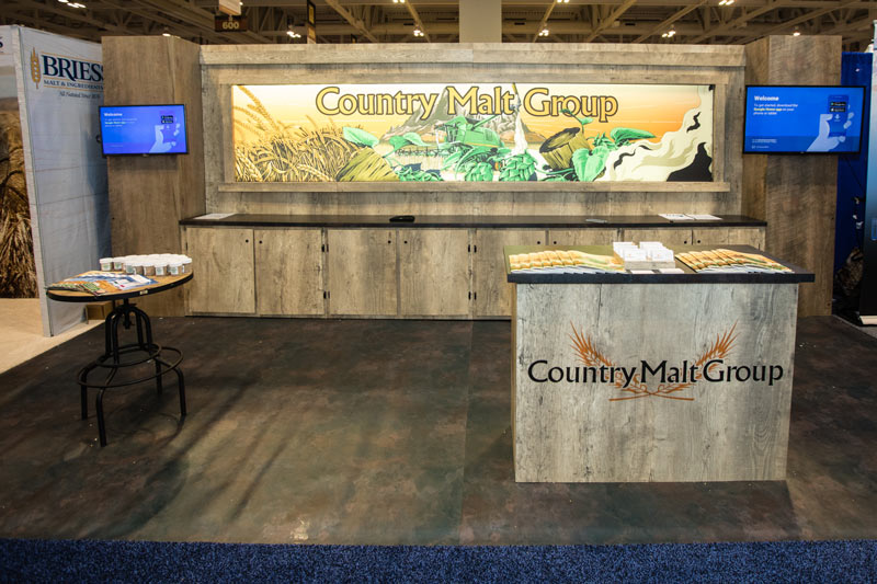 10x20 version of the Country Malt Group trade show booth with two tv monitors mounted to each side of the wall backdrop.
