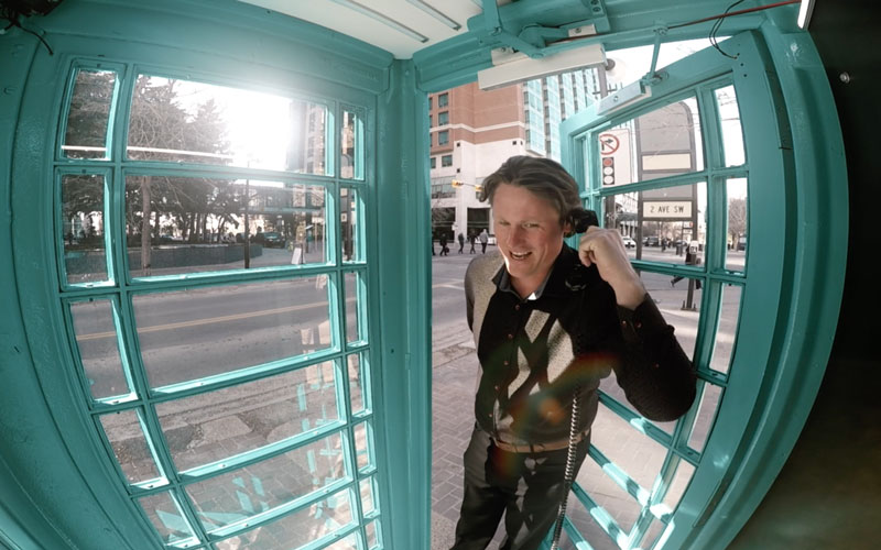 a man inside of a phone booth answering the call to win free flights for an experiential marketing activation