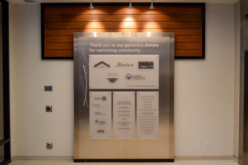 dynamic donor recognition wall in alberta with stainless steel panels, wooden slats, and custom lighting. 