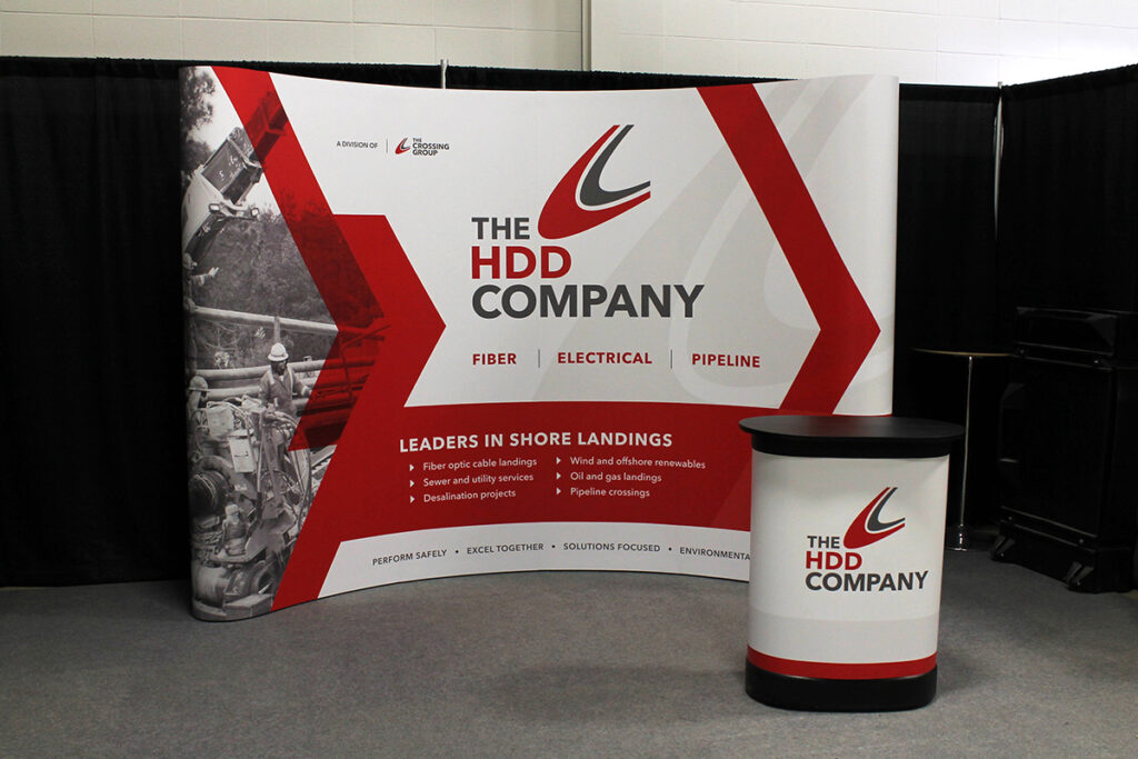 10ft curved portable pop-up display for a trade show even in calgary. A portable branded podium/shipping case is positioned in front. 