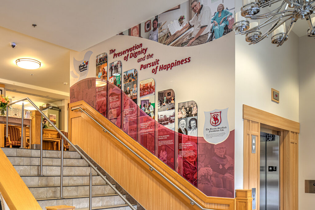 donor recognition wall with a variety of modular acrylic panels and wall graphics above a staircase in Calgary, Alberta. 