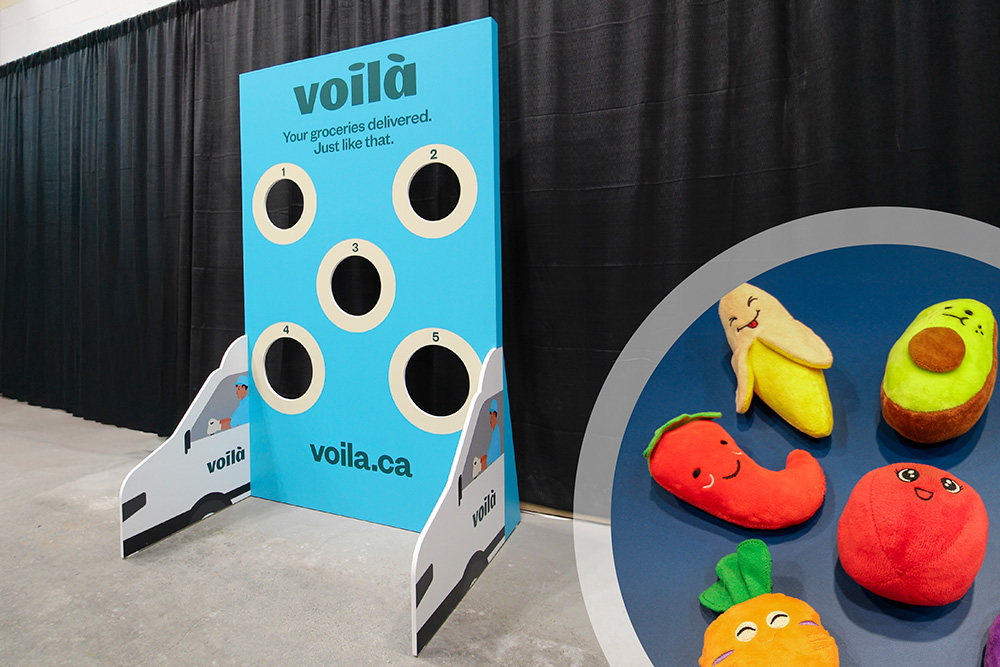 custom cornhole game rental for a grocery delivery company. The vertical feet holding up the game looks like a delivery van on each side. On the right is an inset image showing expressive fruit and vegetable bean bags for the game to try and score points. 