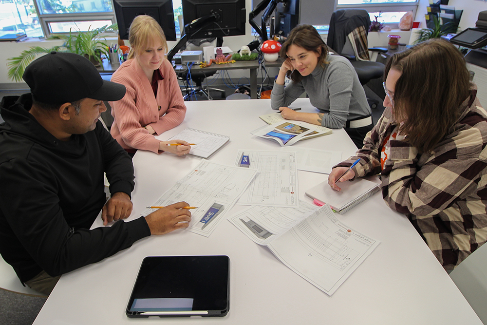 group of graphic designers and industrial designers in Calgary Alberta sitting at a table reviewing a trade show exhibit design.