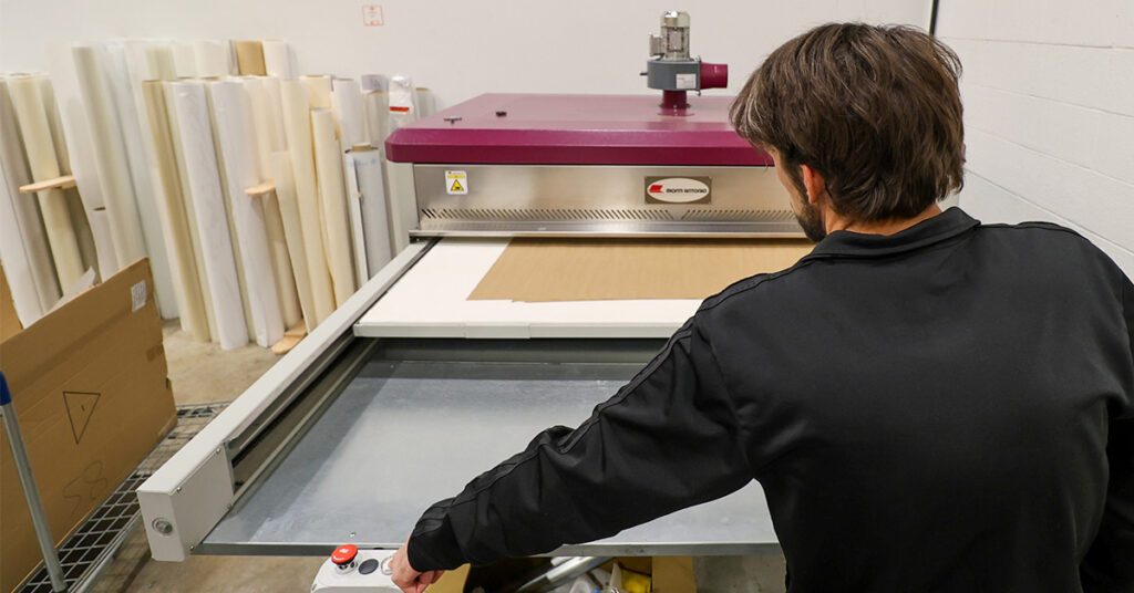 Graphic Technician in Calgary, Alberta, using a Dye Sublimation heat press to create high-quality graphics panels