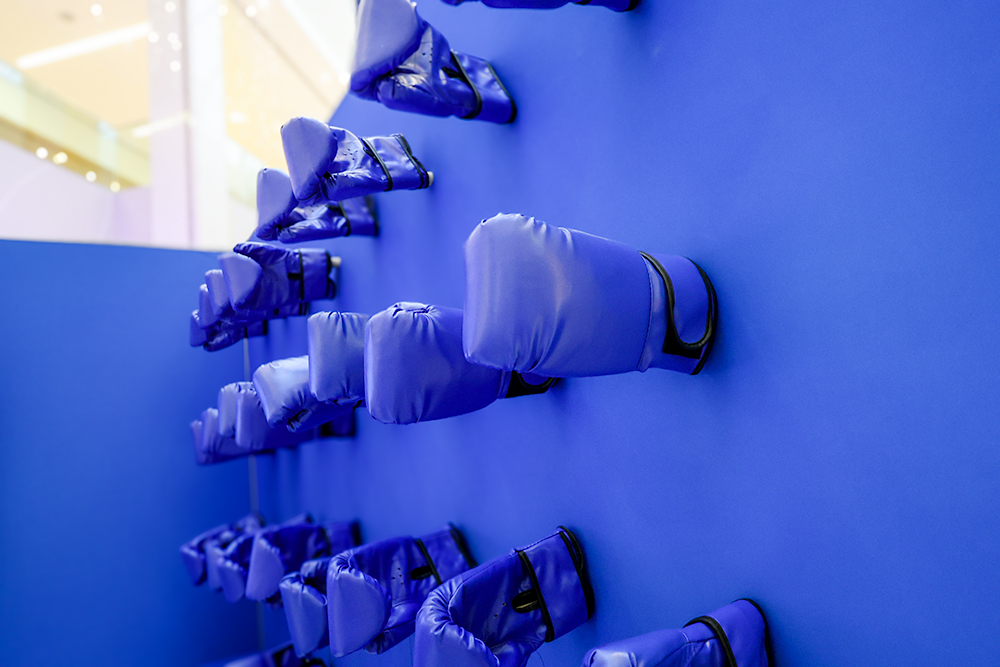 custom display wall with 20 pairs of blue boxing gloves that match the colour of the modular wall behind it. 