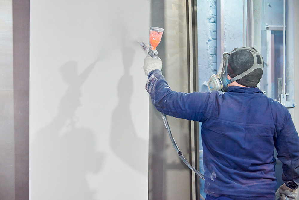 a worker powder coating a graphics panel for dye sublimation print graphics. 